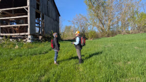 2 people standing in field by a barn