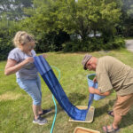 2 people holding long blueprint strip while washing it