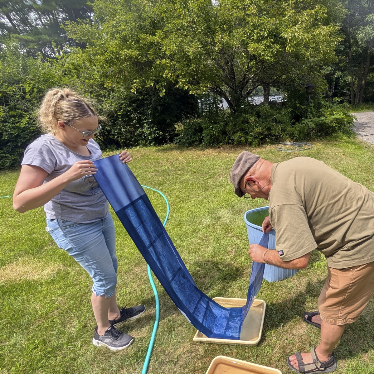 2 people holding long blueprint strip while washing it